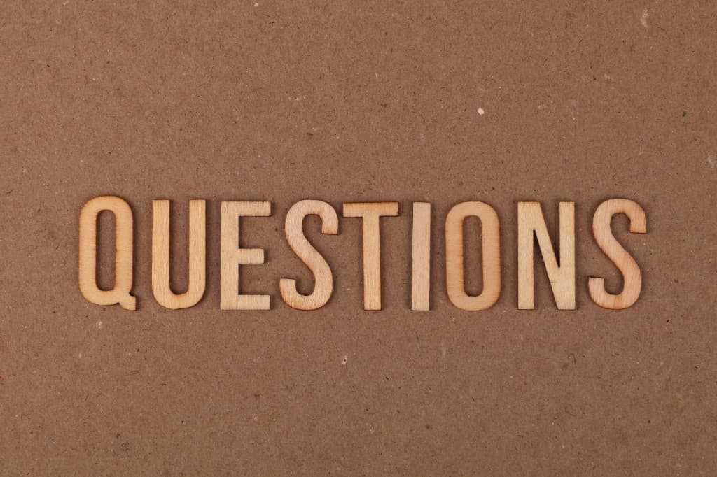 Lettres en bois formant le mot « questions » sur fond kraft
